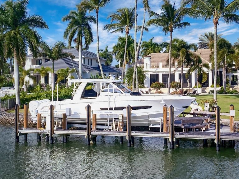 IMM Quality boat lift with stepped top beam holds large white boat in front of waterfront home